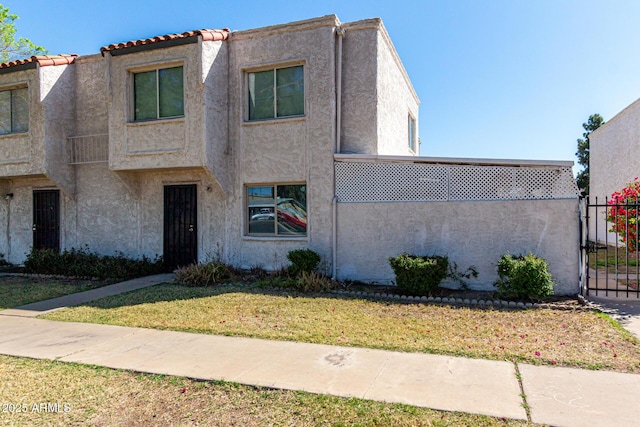 view of front of house with a front yard, a gate, and stucco siding