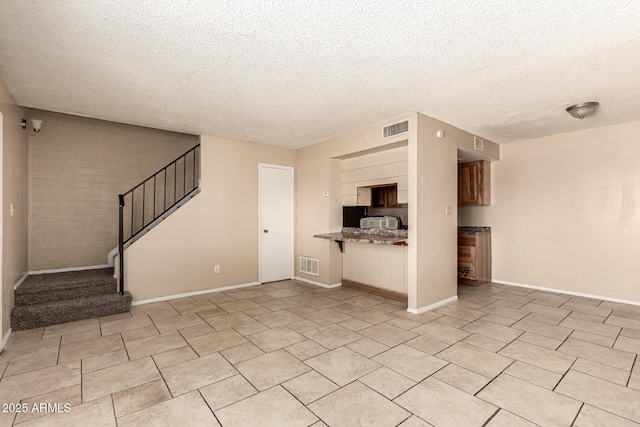 unfurnished living room featuring stairs, visible vents, and a textured ceiling