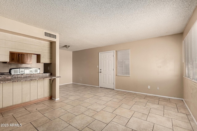 interior space featuring baseboards, visible vents, light tile patterned floors, and a textured ceiling