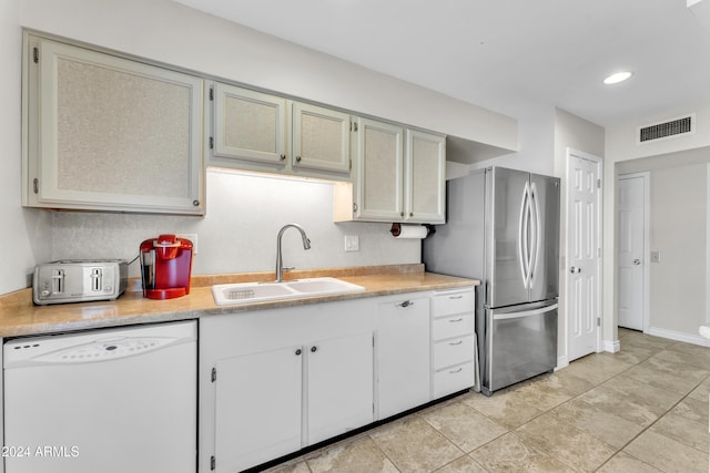 kitchen with dishwasher, light tile patterned floors, sink, and stainless steel refrigerator