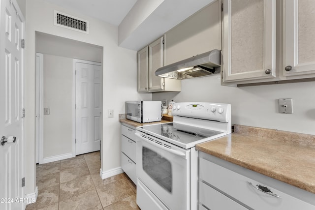 kitchen featuring light tile patterned floors, white appliances, and range hood