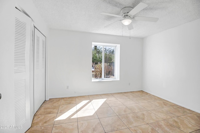 unfurnished bedroom with light tile patterned flooring, ceiling fan, a textured ceiling, and a closet