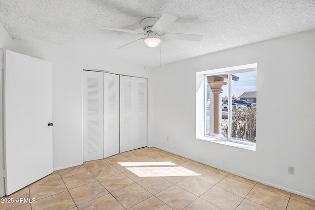 unfurnished bedroom with light tile patterned floors, a closet, a textured ceiling, and ceiling fan