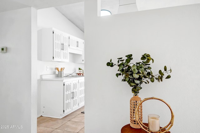 bar featuring white cabinetry, sink, and light tile patterned floors