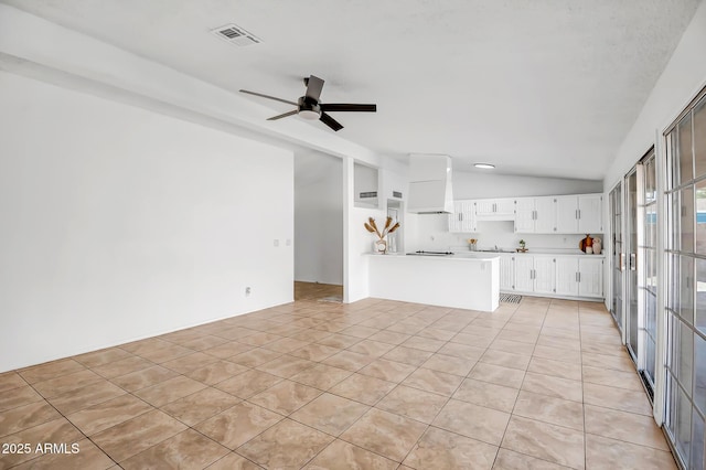 unfurnished living room with ceiling fan, vaulted ceiling, and light tile patterned floors