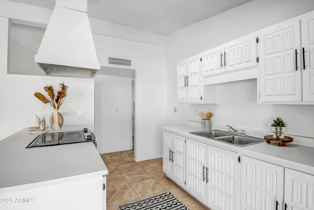 kitchen with sink, island range hood, white cabinets, and light tile patterned flooring