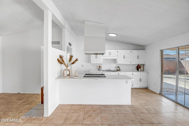 kitchen featuring lofted ceiling, kitchen peninsula, white cabinets, and light tile patterned flooring