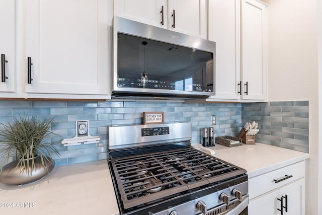 kitchen with backsplash, stainless steel appliances, white cabinets, and light stone countertops