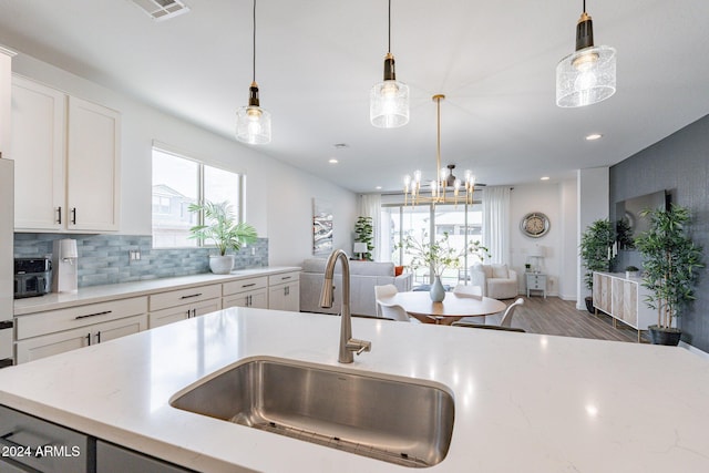 kitchen featuring hardwood / wood-style floors, sink, tasteful backsplash, pendant lighting, and white cabinets