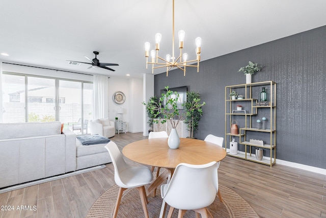 dining area featuring ceiling fan with notable chandelier and wood-type flooring