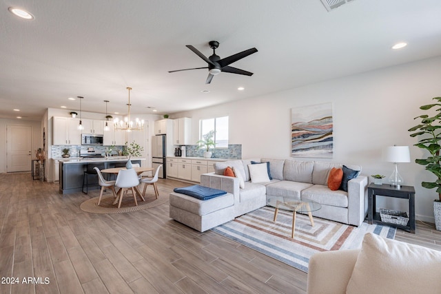 living room featuring light wood-type flooring and ceiling fan with notable chandelier