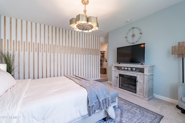 carpeted bedroom with a spacious closet, an inviting chandelier, and a closet