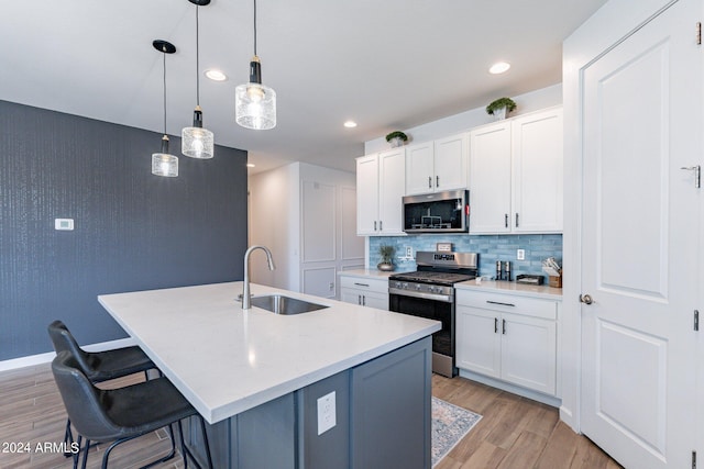 kitchen featuring backsplash, light hardwood / wood-style floors, sink, decorative light fixtures, and stainless steel appliances