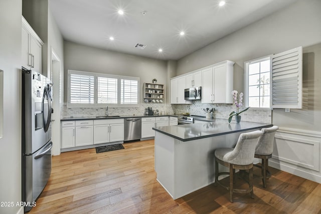 kitchen featuring a sink, stainless steel appliances, dark countertops, and a peninsula