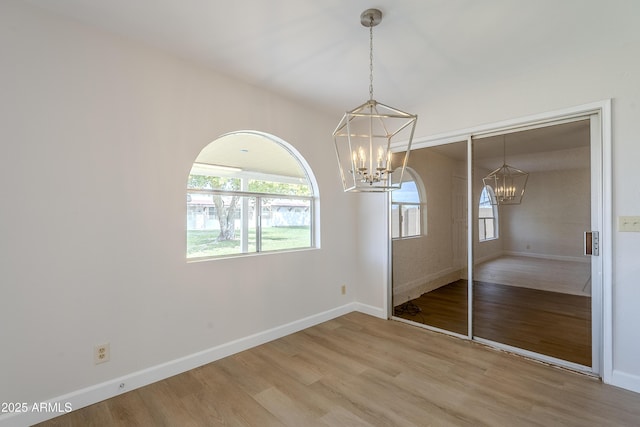 unfurnished bedroom featuring hardwood / wood-style flooring, a notable chandelier, and a closet