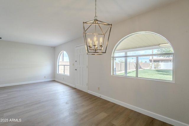 unfurnished room featuring hardwood / wood-style flooring and an inviting chandelier