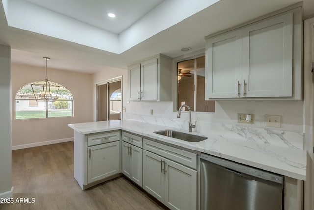 kitchen featuring sink, dishwasher, light stone counters, kitchen peninsula, and light wood-type flooring