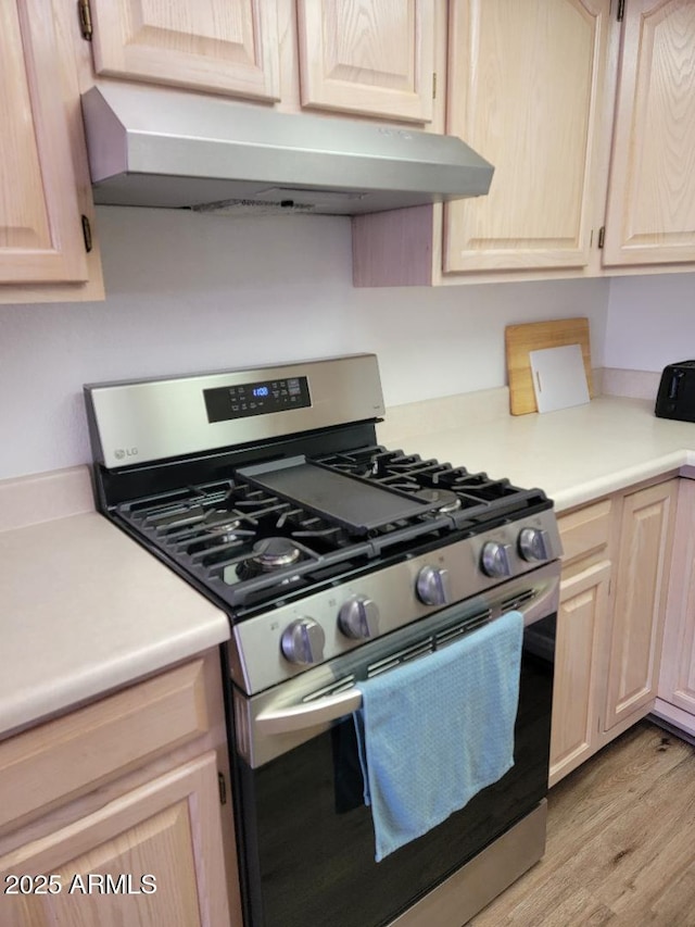 311 E Lancaster Ct, Florence, AZ 85132 - kitchen featuring light wood-type flooring, light brown cabinetry, under cabinet range hood, stainless steel range with gas cooktop, and light countertops