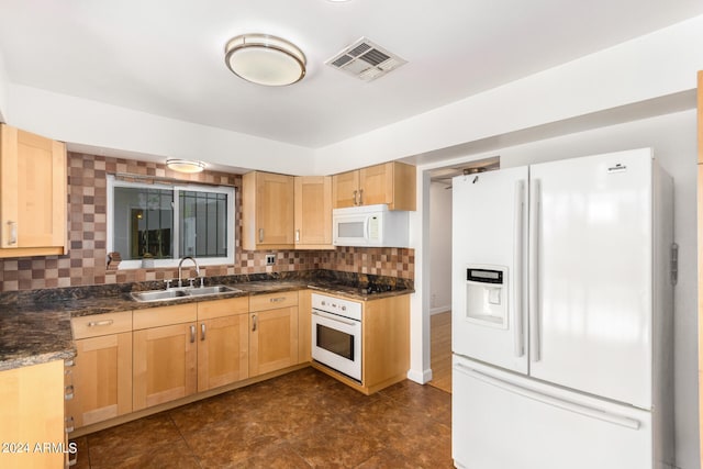 kitchen featuring backsplash, white appliances, light brown cabinets, dark stone counters, and sink