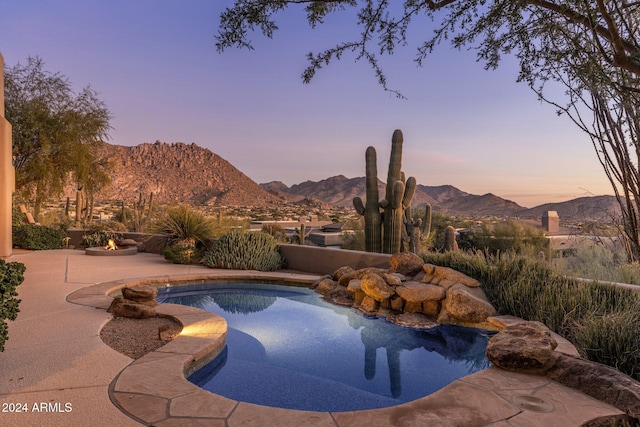 pool at dusk with a mountain view and a patio