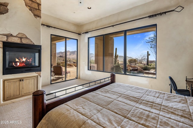 bedroom with a mountain view, carpet flooring, access to exterior, a fireplace, and multiple windows