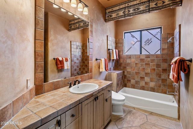 full bathroom featuring vanity, tiled shower / bath combo, and toilet