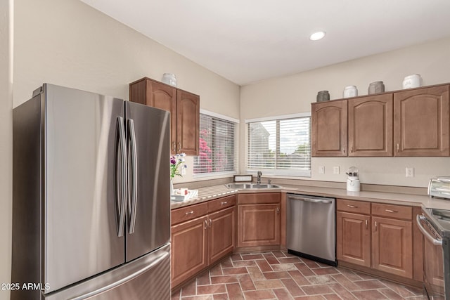 kitchen featuring a sink, appliances with stainless steel finishes, brick patterned floor, and light countertops