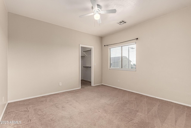 unfurnished bedroom featuring baseboards, a walk in closet, carpet, and visible vents