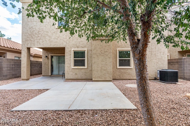rear view of house featuring central air condition unit, stucco siding, a fenced backyard, and a patio area