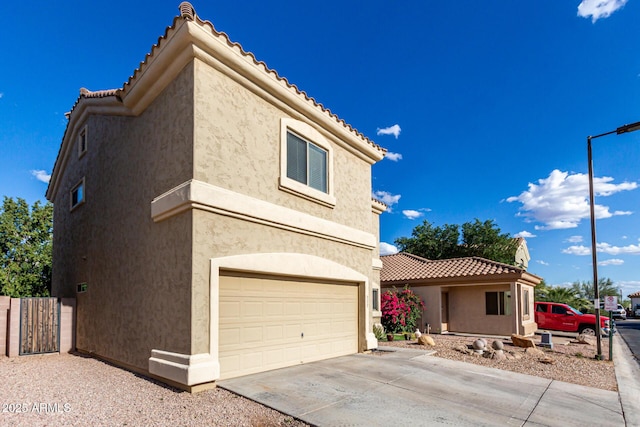view of front of home featuring a garage, stucco siding, driveway, and a tiled roof
