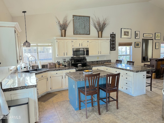 kitchen with sink, hanging light fixtures, a kitchen bar, stainless steel appliances, and a kitchen island