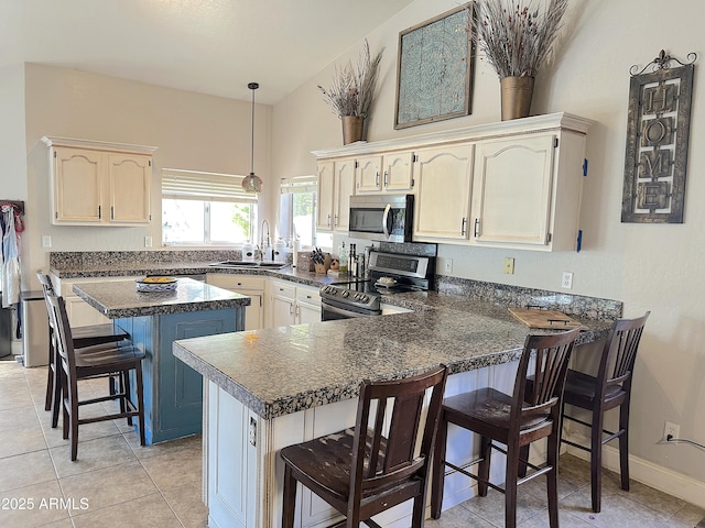 kitchen featuring appliances with stainless steel finishes, sink, a breakfast bar area, light tile patterned floors, and kitchen peninsula