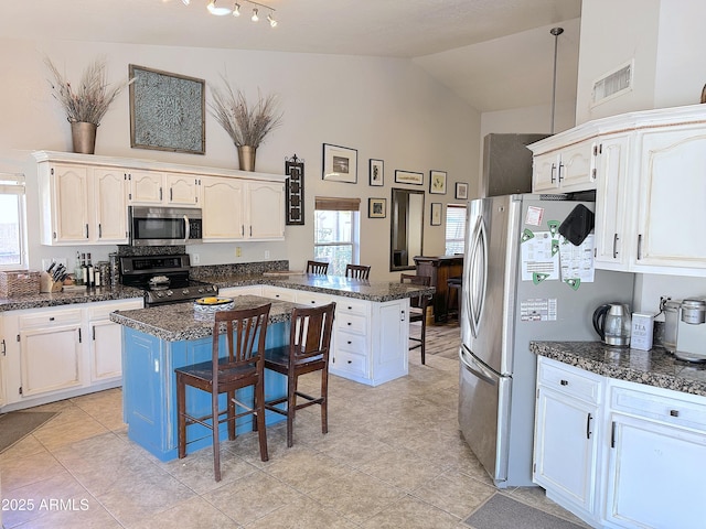 kitchen featuring a kitchen island, a breakfast bar, lofted ceiling, and appliances with stainless steel finishes