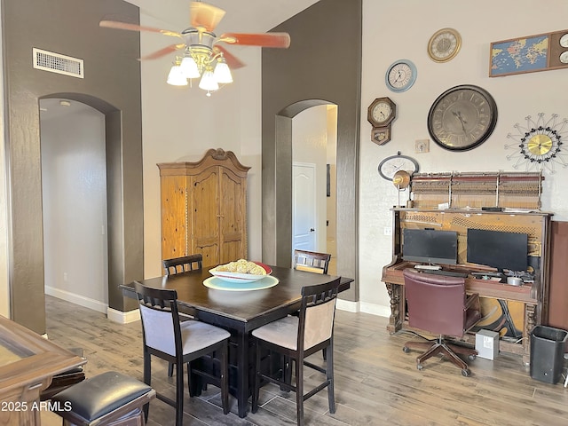 dining area with hardwood / wood-style flooring, ceiling fan, and a high ceiling