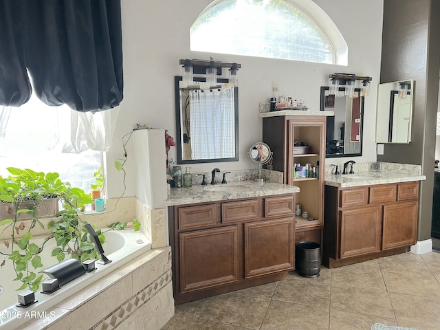 bathroom with vanity, a relaxing tiled tub, and tile patterned floors