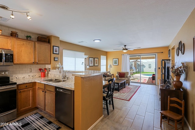 kitchen with light wood-type flooring, appliances with stainless steel finishes, sink, a kitchen breakfast bar, and kitchen peninsula