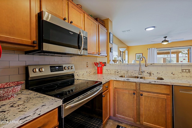 kitchen with stainless steel appliances, sink, tasteful backsplash, ceiling fan, and light stone countertops