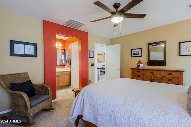 bedroom with ensuite bathroom, light colored carpet, and ceiling fan