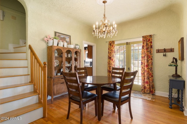 dining area featuring a chandelier, french doors, wood-type flooring, and a textured ceiling