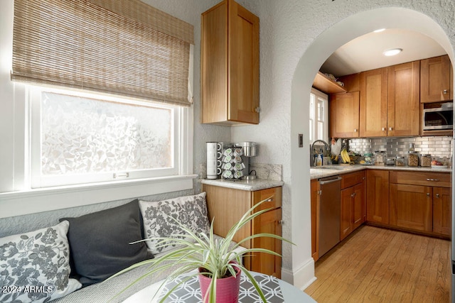 kitchen featuring appliances with stainless steel finishes, light wood-type flooring, a healthy amount of sunlight, and sink