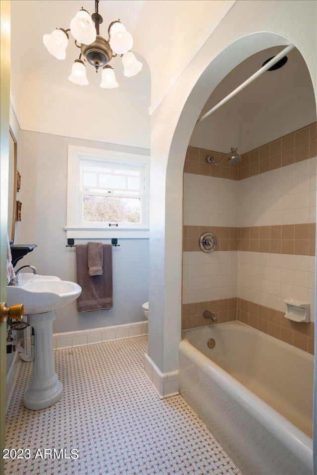 bathroom featuring toilet, a notable chandelier, tiled shower / bath, and tile patterned flooring