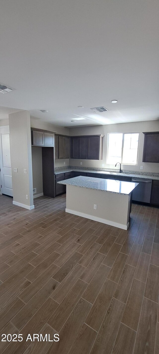 15587 S 180th Ln, Goodyear, AZ 85338 - kitchen featuring dark wood-style flooring, stainless steel dishwasher, a center island, and baseboards