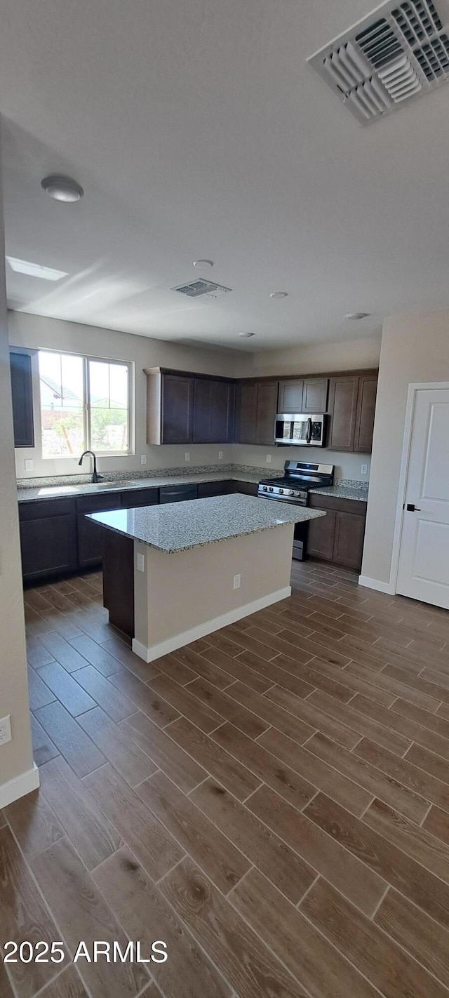 15587 S 180th Ln, Goodyear, AZ 85338 - kitchen with appliances with stainless steel finishes, a center island, wood finish floors, and light stone counters