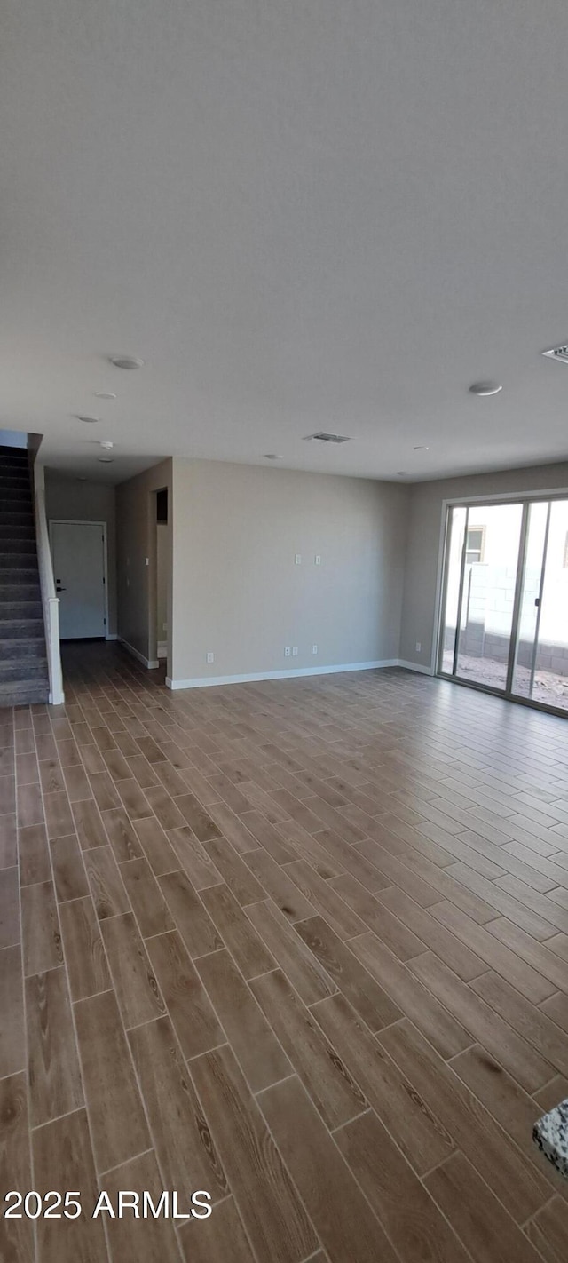 15587 S 180th Ln, Goodyear, AZ 85338 - unfurnished living room featuring wood tiled floors, stairway, and baseboards