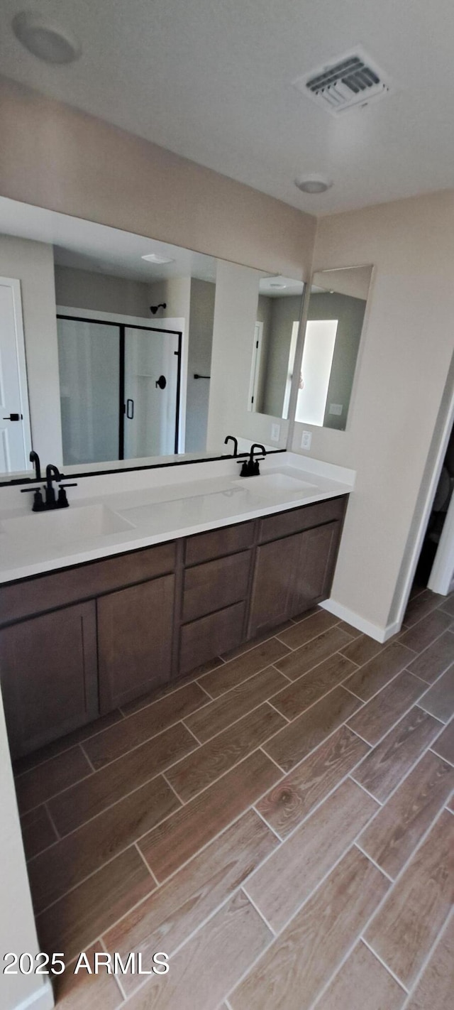 15587 S 180th Ln, Goodyear, AZ 85338 - bathroom featuring wood tiled floors, a shower stall, double vanity, and baseboards