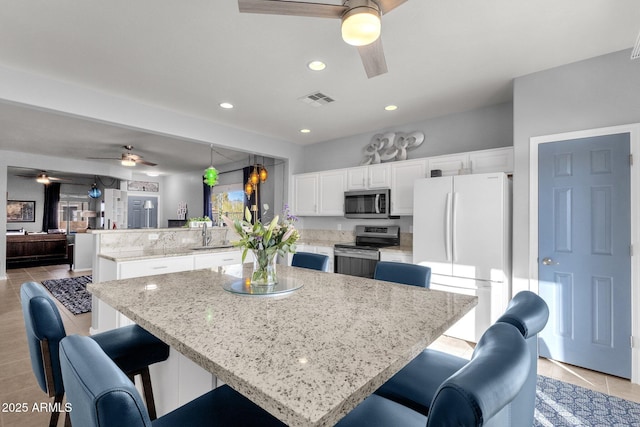 kitchen featuring visible vents, appliances with stainless steel finishes, open floor plan, decorative light fixtures, and a peninsula