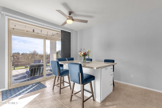 dining space with light tile patterned floors, a ceiling fan, and baseboards