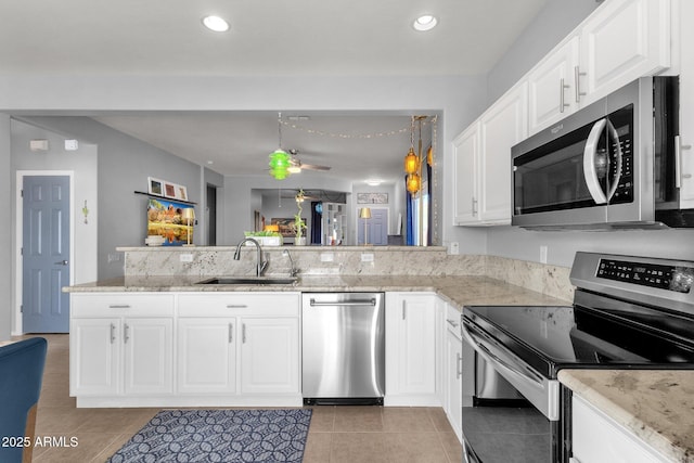 kitchen with appliances with stainless steel finishes, white cabinets, a sink, and a peninsula