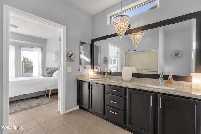 ensuite bathroom with an inviting chandelier, a sink, tile patterned flooring, and connected bathroom