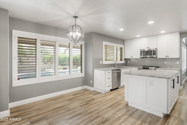kitchen with appliances with stainless steel finishes, a sink, baseboards, plenty of natural light, and recessed lighting